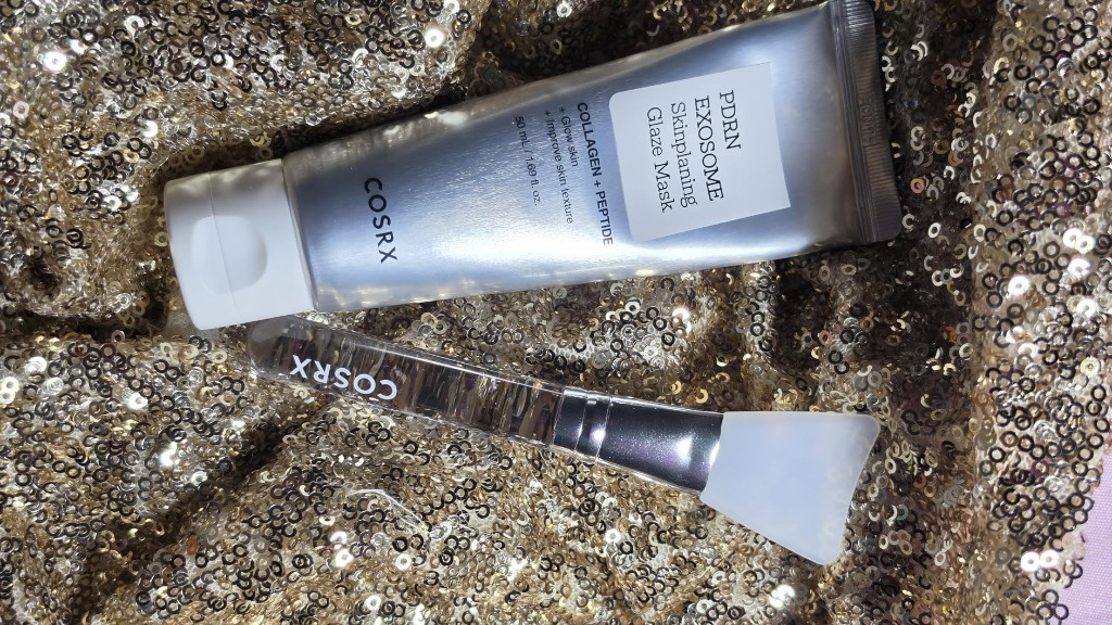 COSRX PDRN Exosome Glaze Mask tube and spatula set on luxury gold fabric