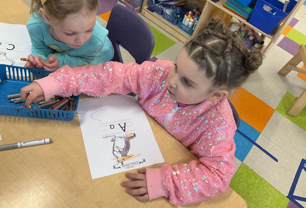Girl coloring in classroom wearing pink sparkly jacket