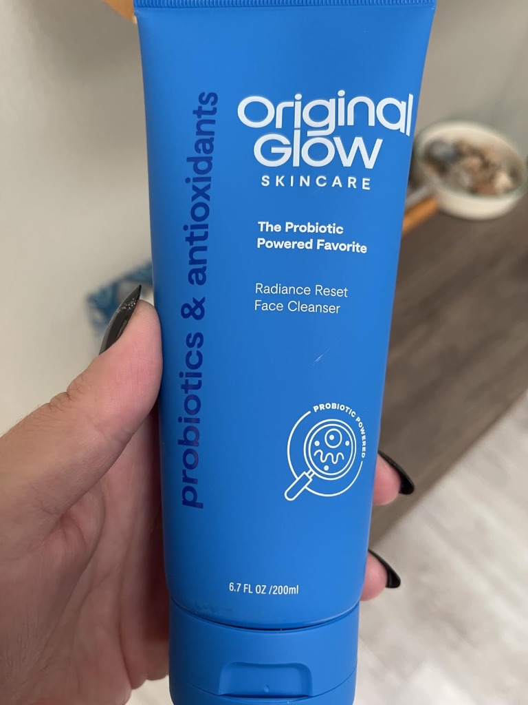 Holding 6.7 FL OZ bottle of Original Glow Cleanser
