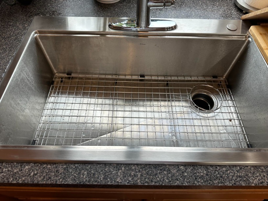 Spacious 9-inch deep stainless steel basin with bottom protective grid and rear offset drain