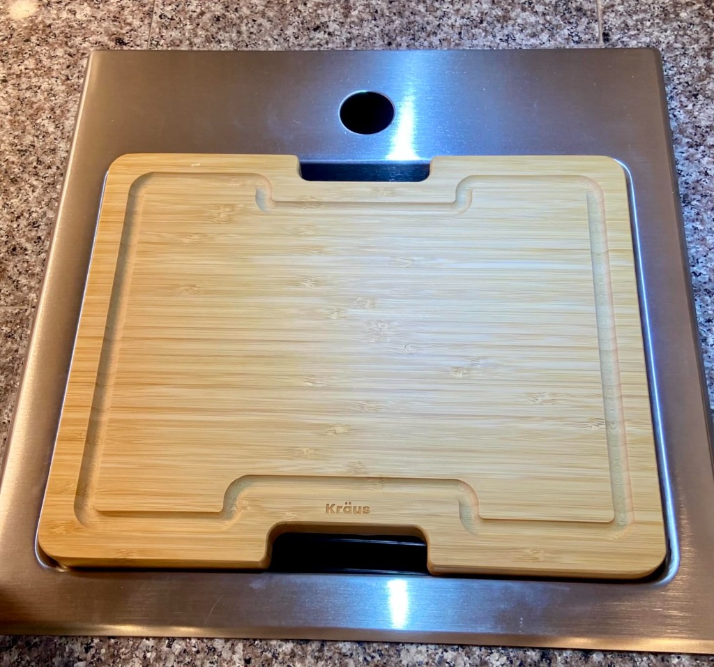 Close-up of the custom bamboo cutting board resting snugly on the KRAUS integrated ledge