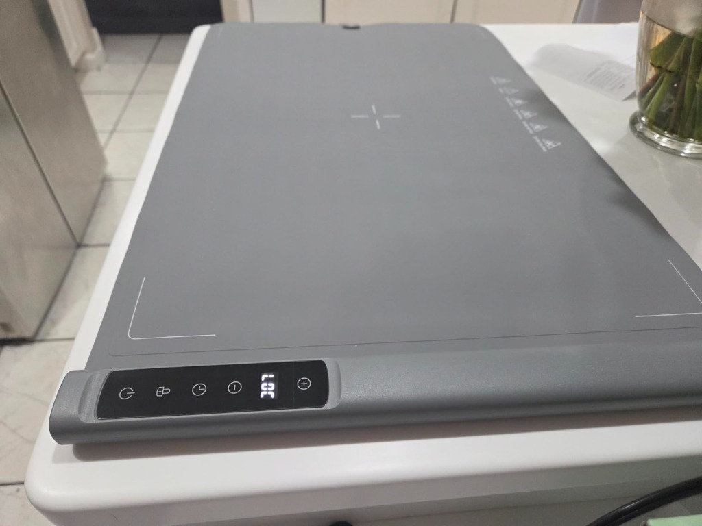 Real photo of food warming mat on kitchen counter with digital touch panel showing LOC display